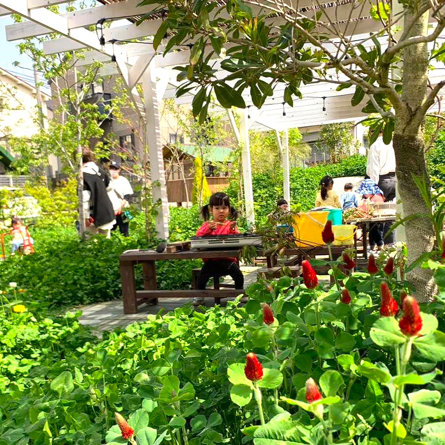 園庭で植物あそびをするこども